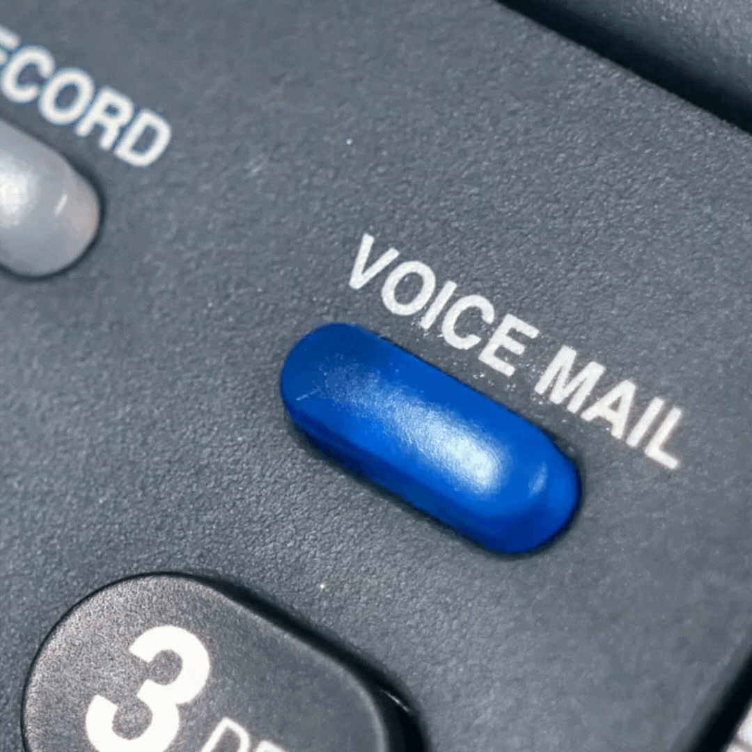 Close-up of a voicemail button on an office phone representing missed client calls in a law firm.